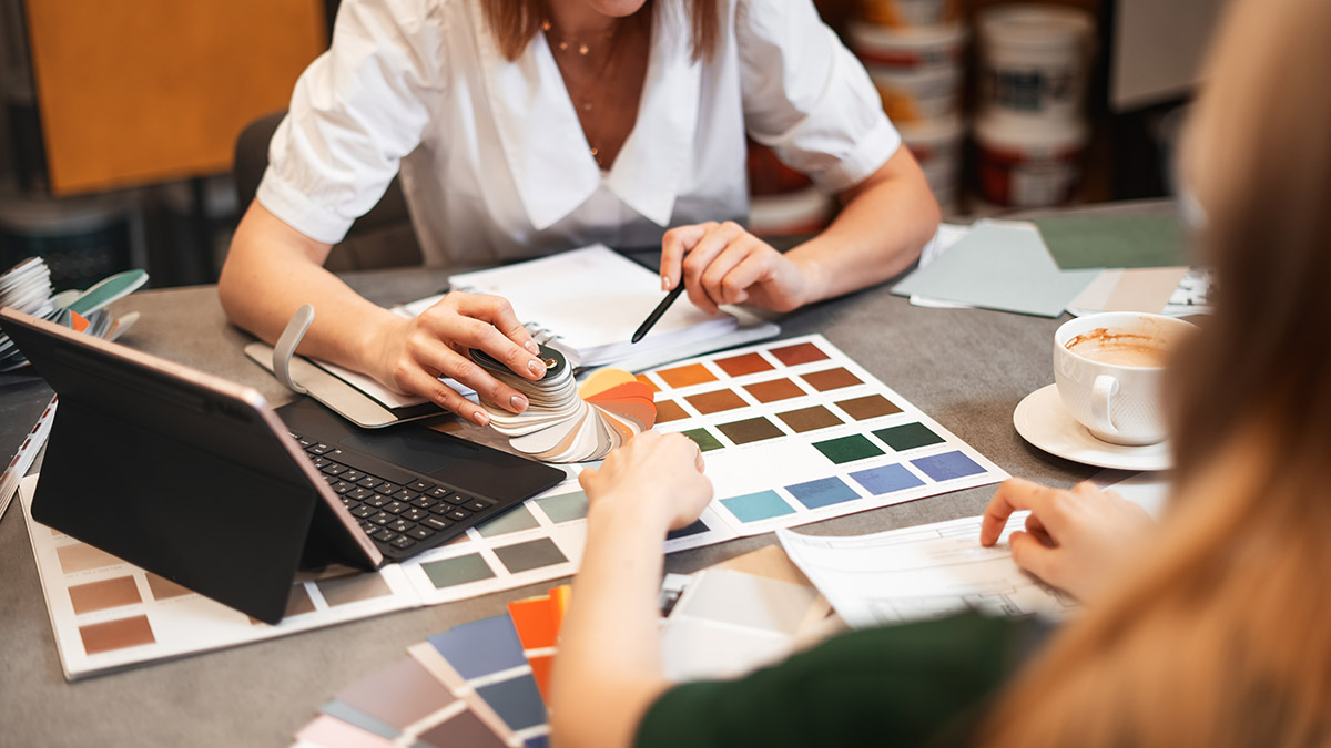 Close,Up,Hand,Choosing,Color,From,Color,Sample,Swatch.,The A homeowner choosing from color sample swatches.
